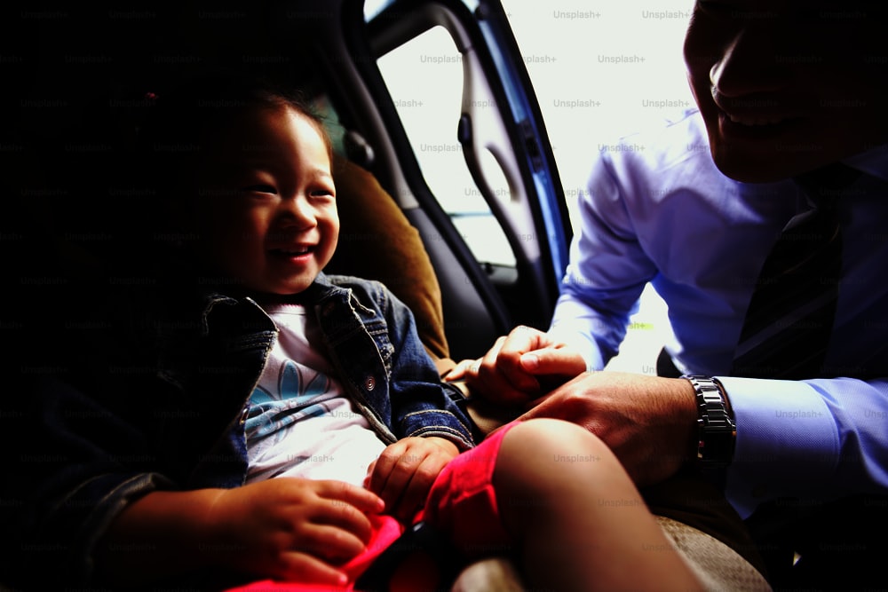 a little girl sitting in a car seat next to a man