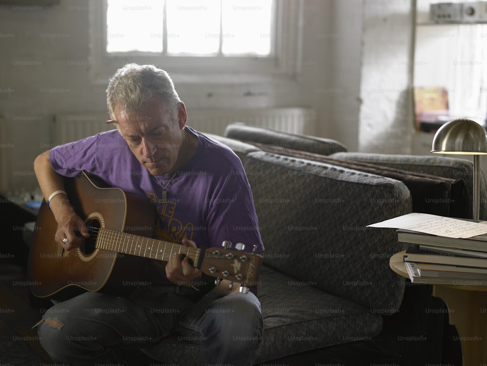 a man sitting on a couch playing a guitar