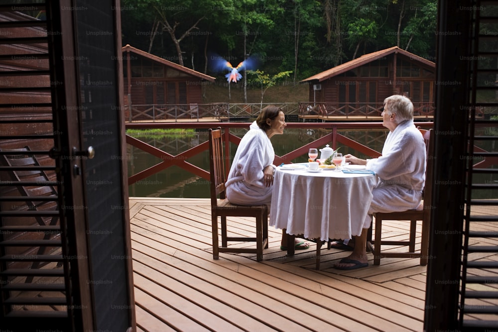 duas mulheres sentadas em uma mesa em um deck