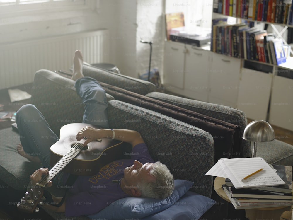 a man laying on a couch with a guitar