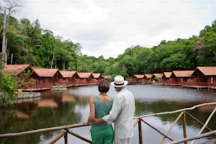 a man and a woman standing on a bridge looking at the water