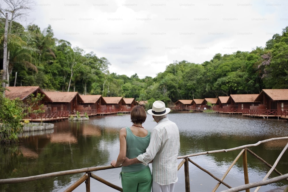 a man and a woman standing on a bridge looking at the water