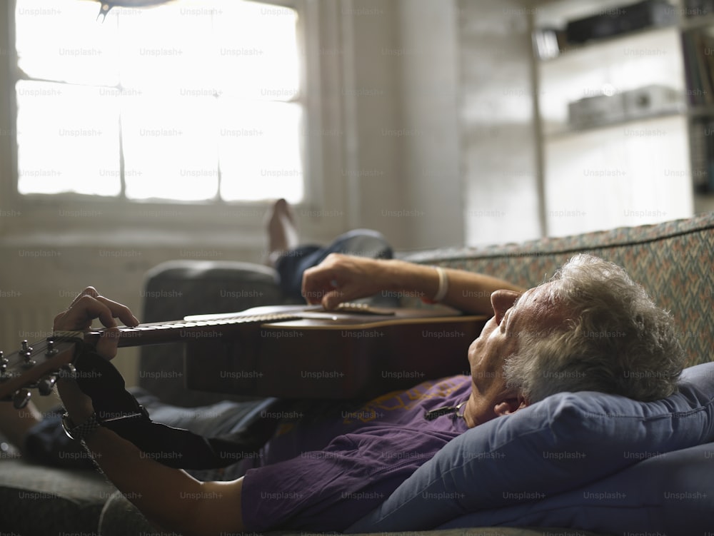Una mujer acostada encima de un sofá sosteniendo una guitarra