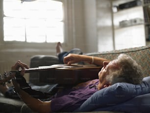 a woman laying on top of a couch holding a guitar