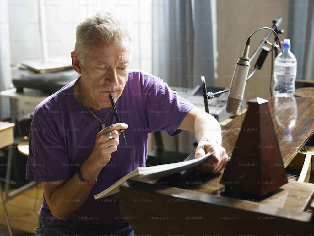 Un hombre con una camisa púrpura escribiendo en un pedazo de papel