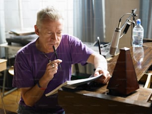 Ein Mann in einem lila Hemd schreibt auf ein Blatt Papier