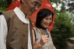 Un hombre y una mujer sonríen mientras sostienen un paraguas