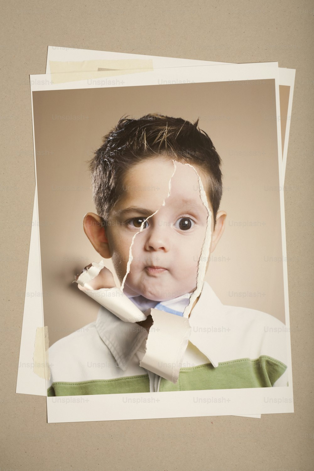 Ein kleiner Junge mit einem zerrissenen Stück Papier im Gesicht