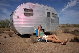 a woman sitting in a chair in front of a trailer