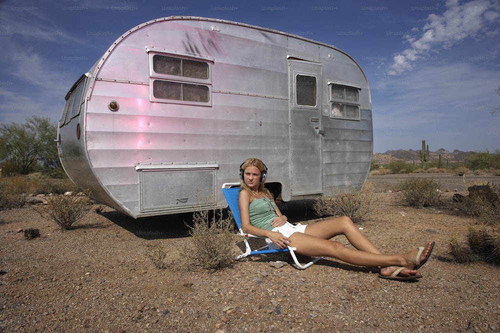 a woman sitting in a chair in front of a trailer