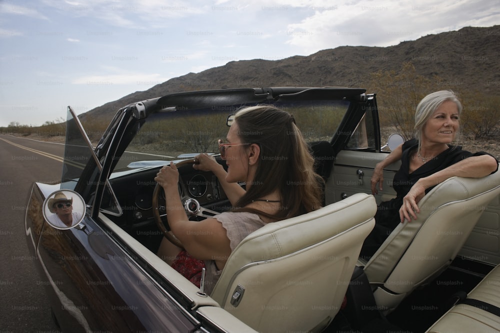 a woman sitting in the back of a convertible car