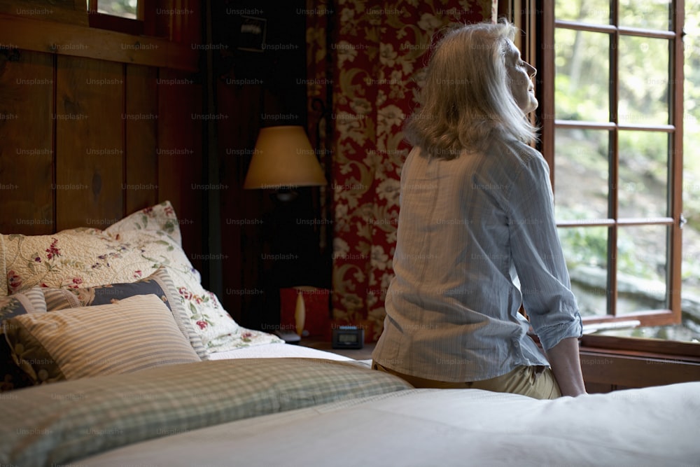 a woman standing on a bed looking out a window