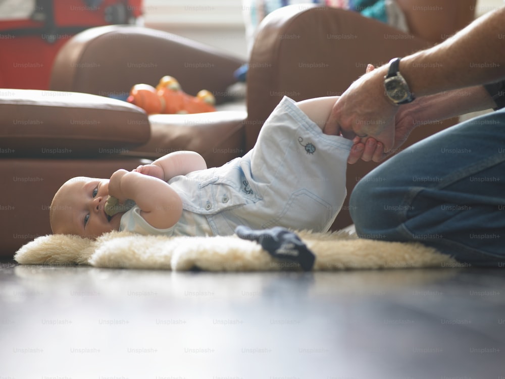 a baby laying on the floor with a person holding it
