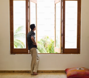 a man standing in front of a window looking out