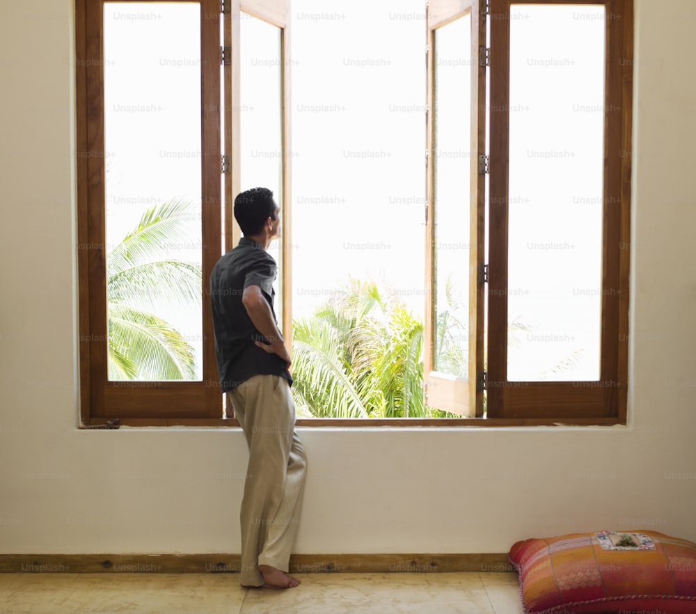 a man standing in front of a window looking out