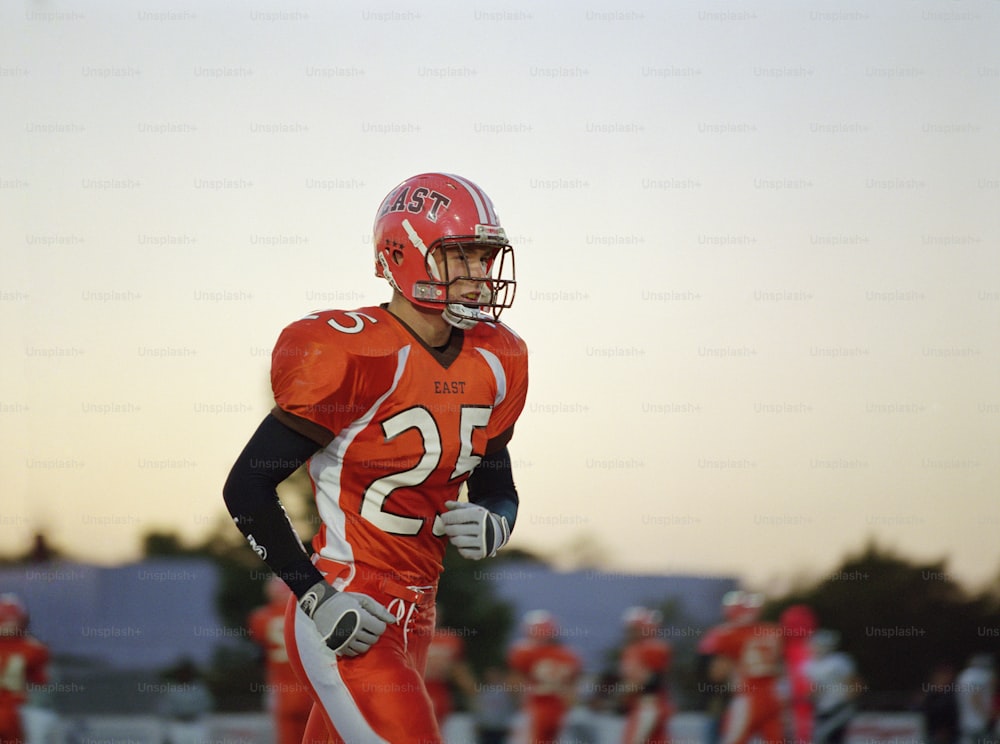 a football player wearing an orange uniform and holding a football