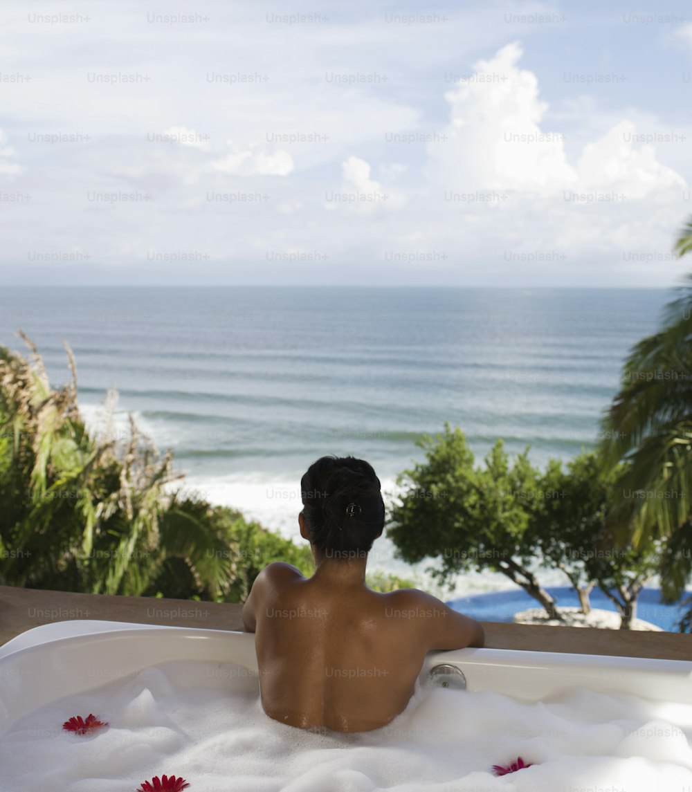 a man sitting in a jacuzzi overlooking the ocean