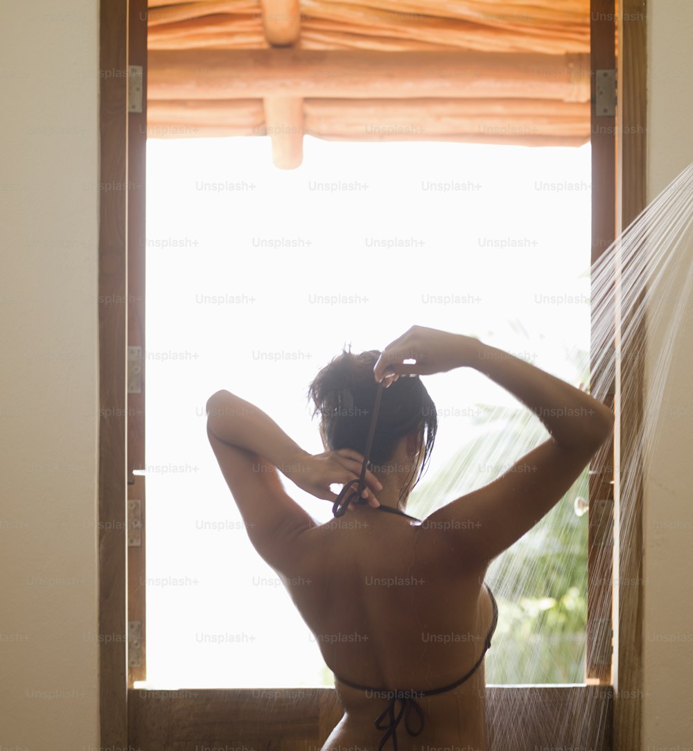 a woman in a bikini standing in front of a window