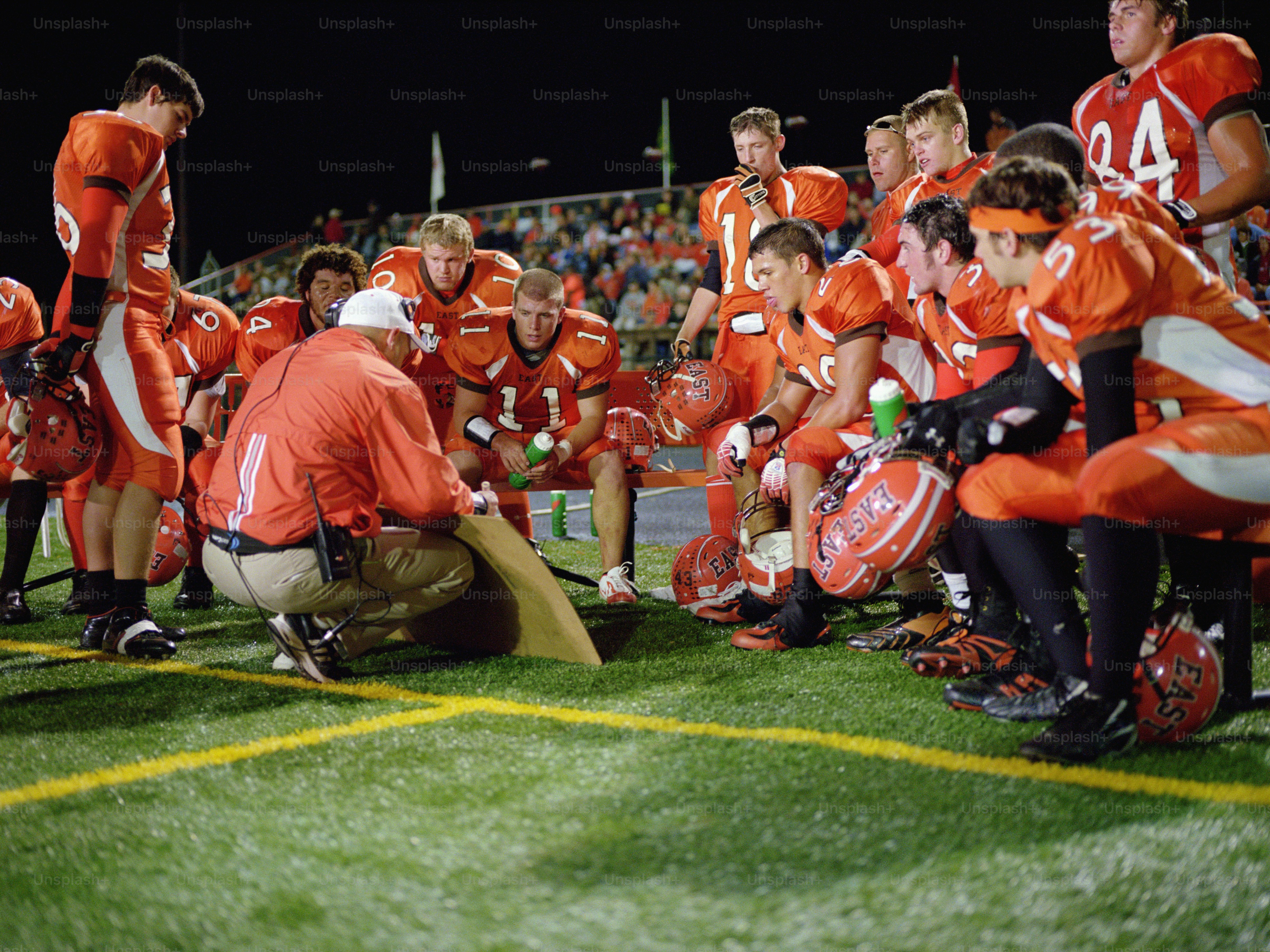 a group of football players kneel down on the field