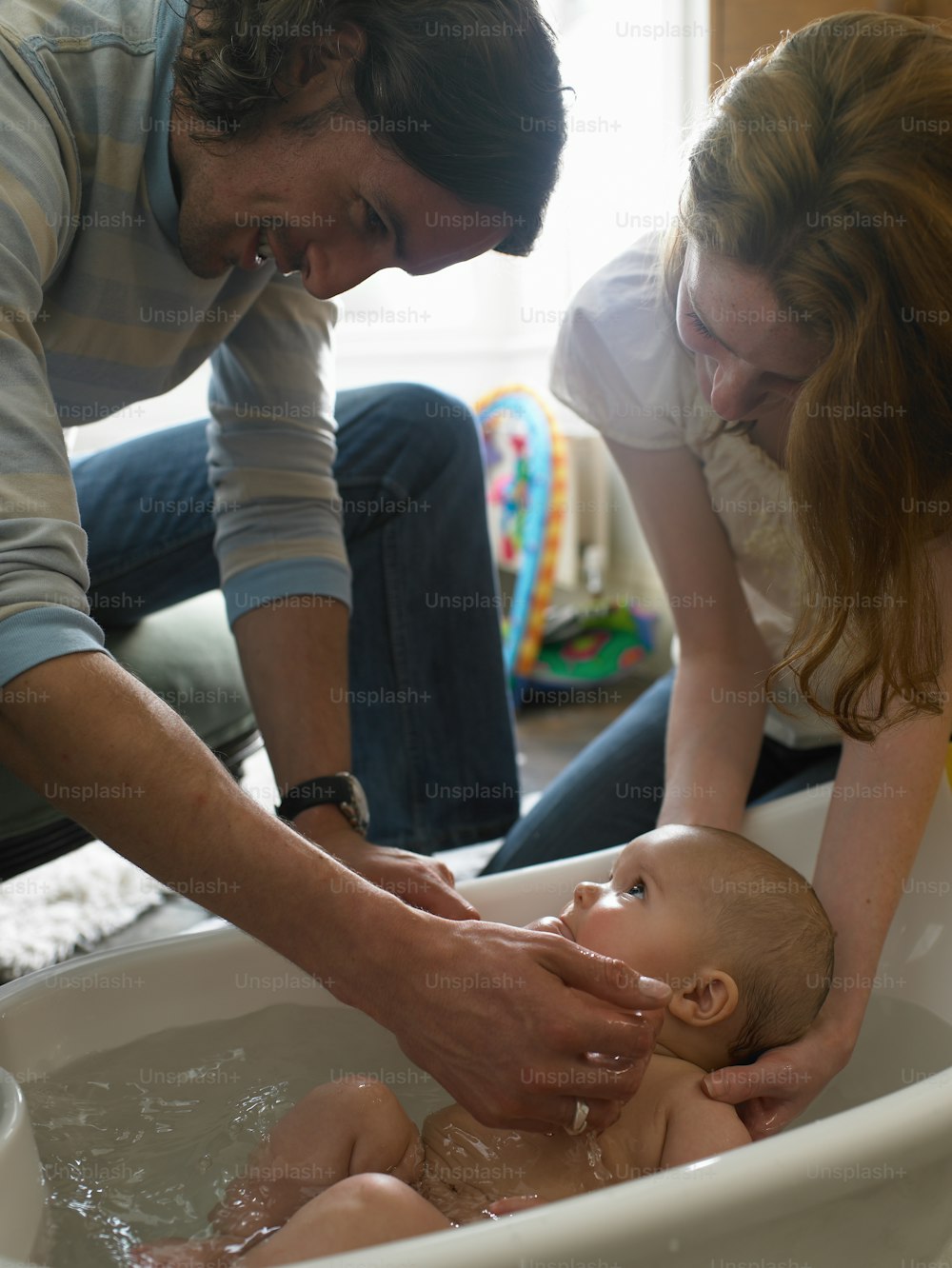a man and woman washing a baby in a bath tub