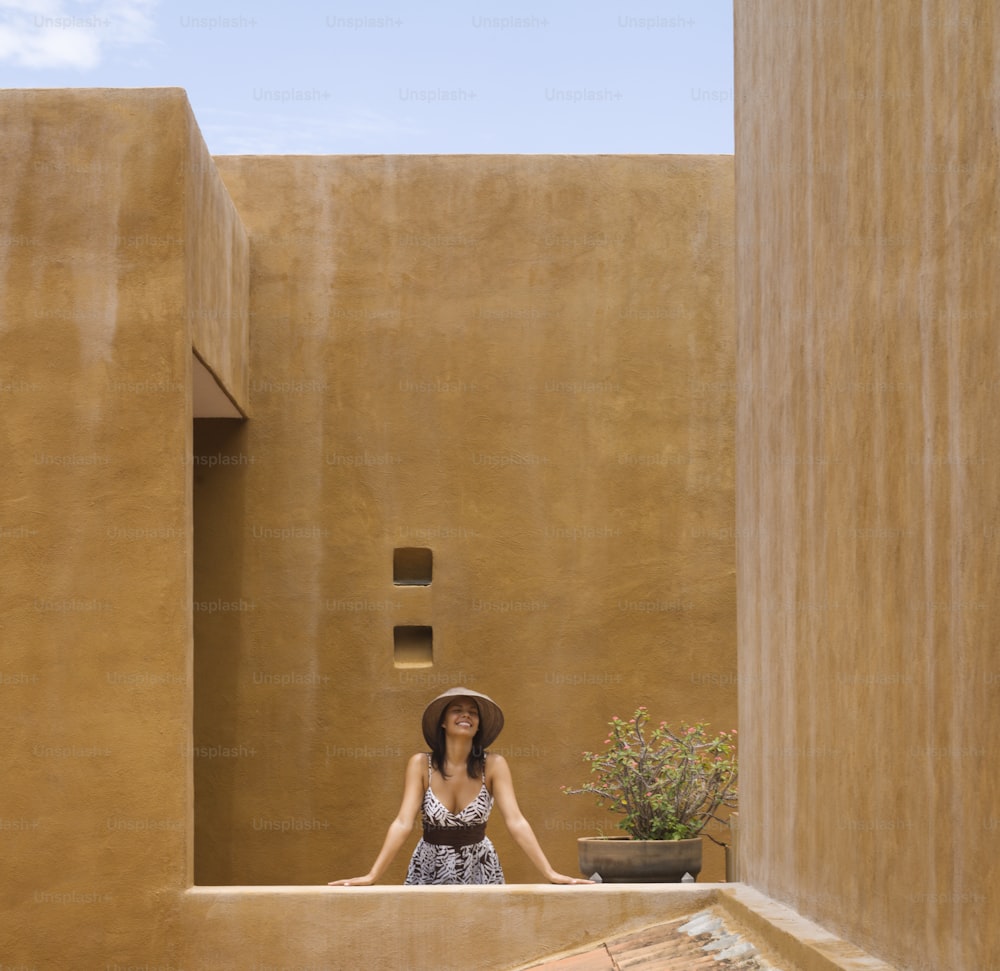 a woman standing on a balcony with a hat on