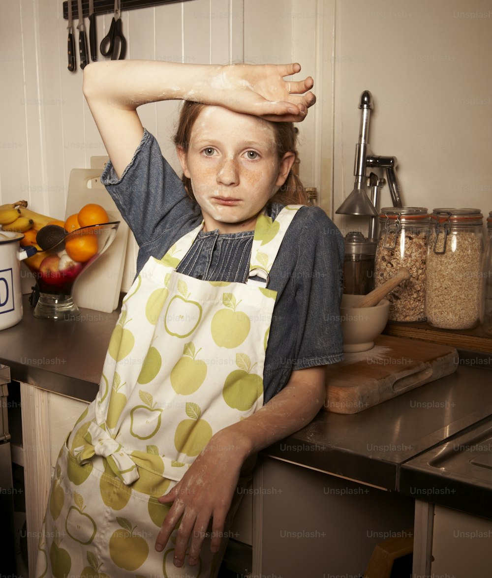 a young girl in a kitchen holding her hands on her head