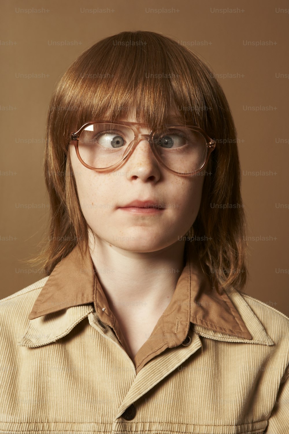 a woman wearing glasses and a brown shirt