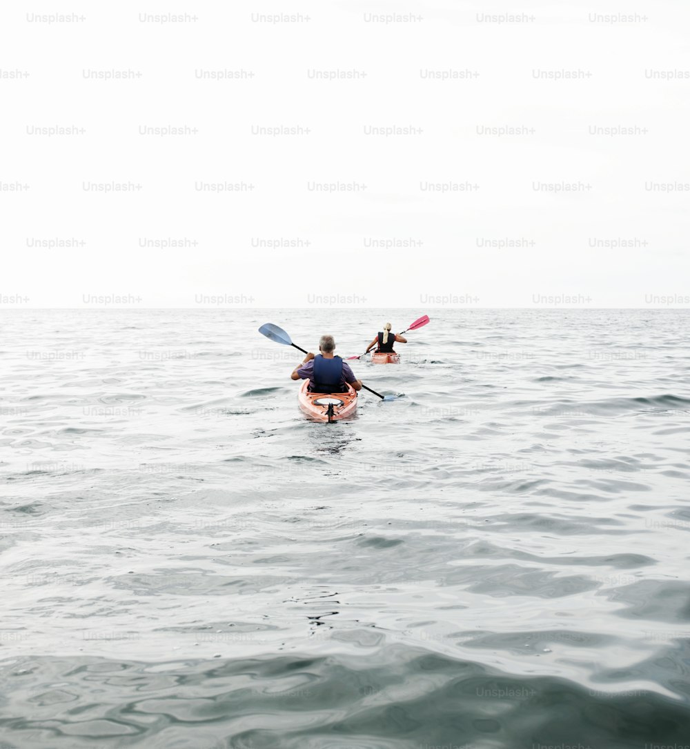 two people in kayaks paddling in the ocean