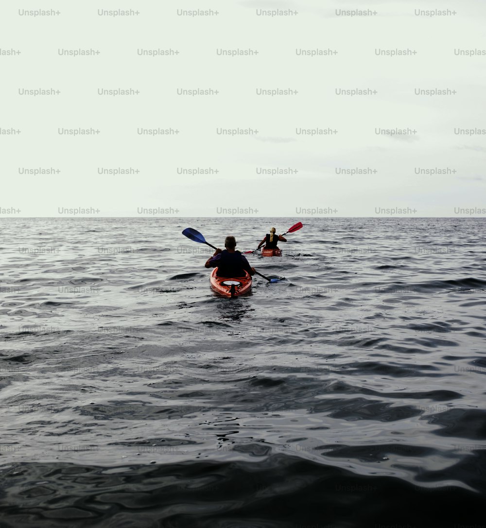 two people in kayaks paddling in the ocean