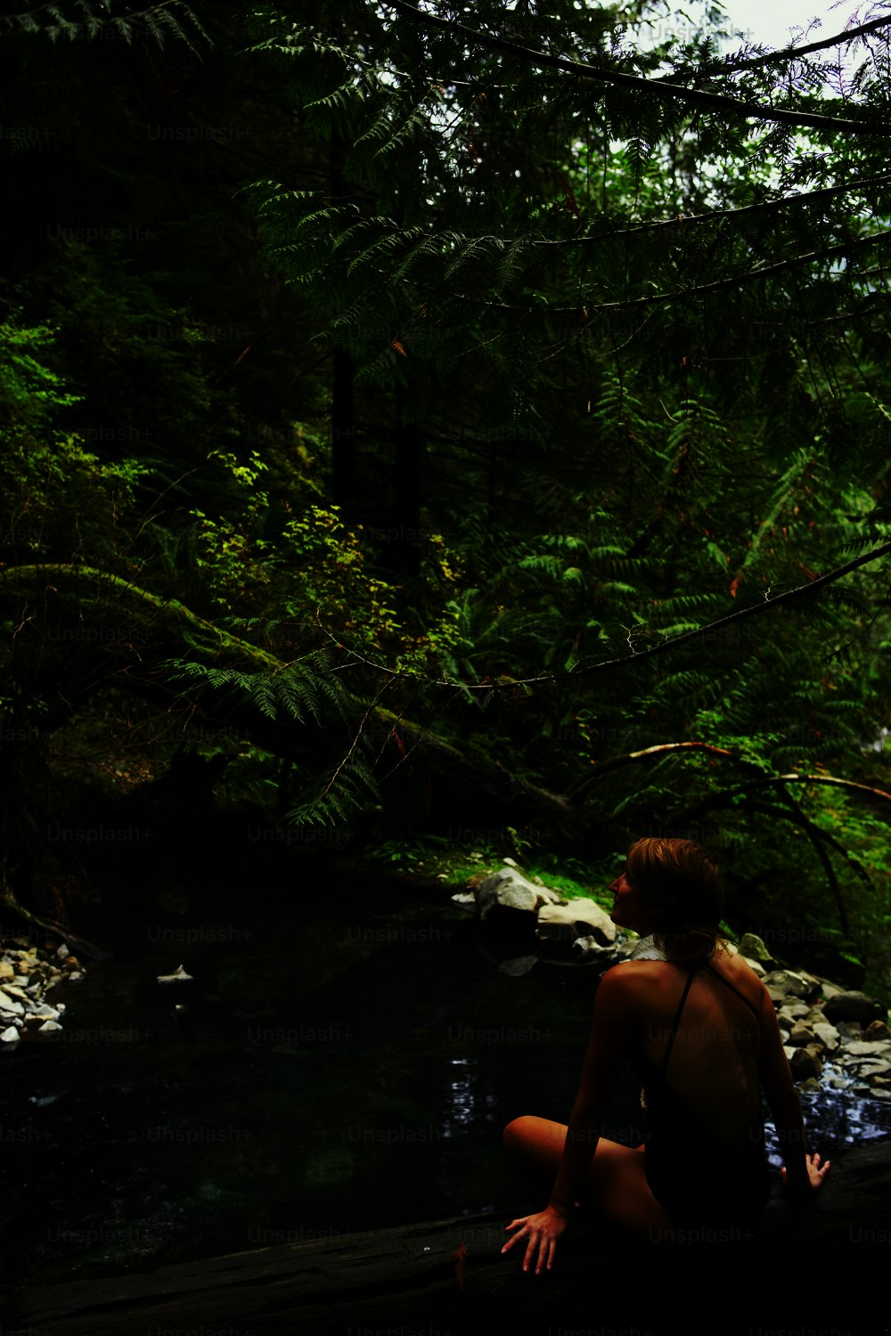 a woman sitting on a log in the woods