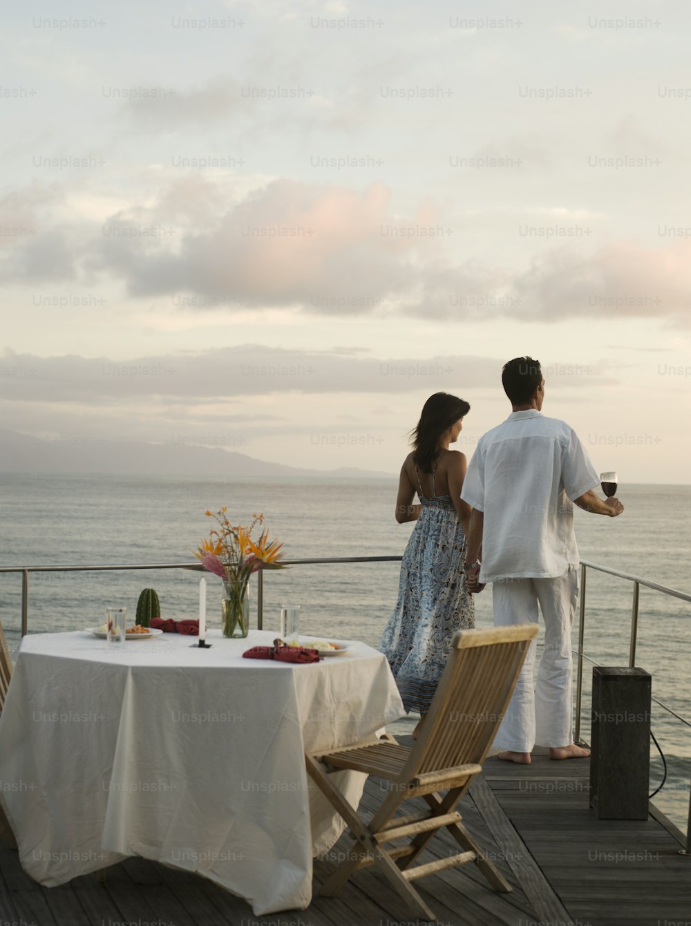 a man and a woman standing on a deck overlooking the ocean
