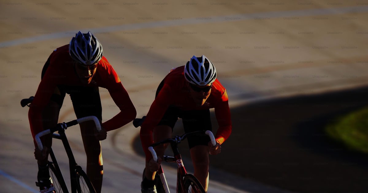 Two bicyclists racing down a paved road photo – Racing bike Image on ...