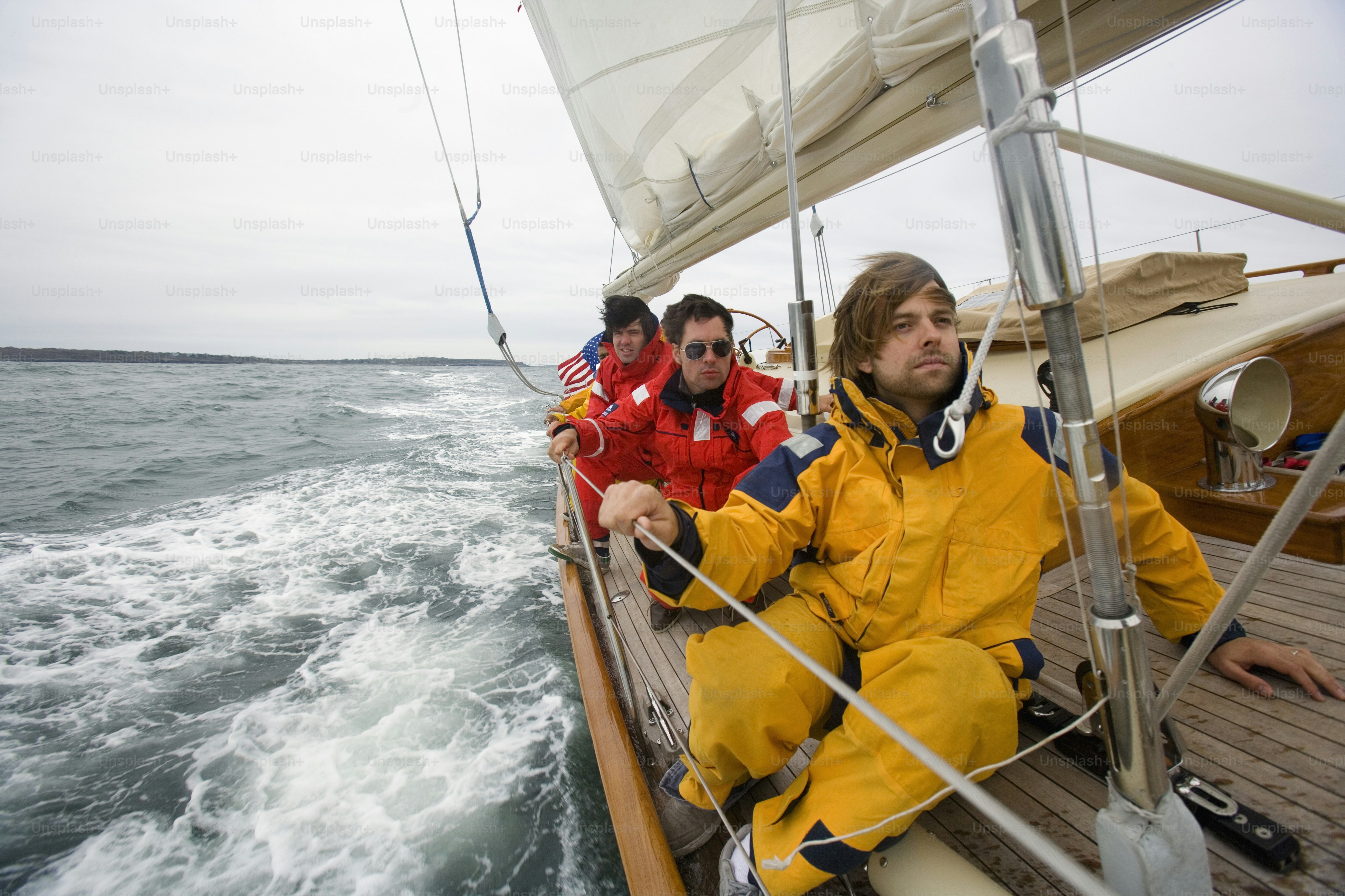 A couple of men riding on the back of a boat photo – Sail boat Image on ...