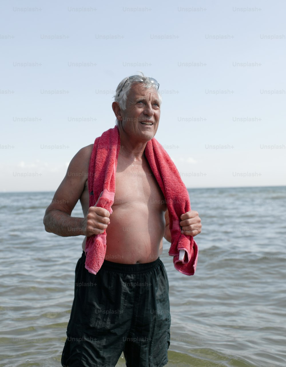 a man standing in the water with a towel around his neck