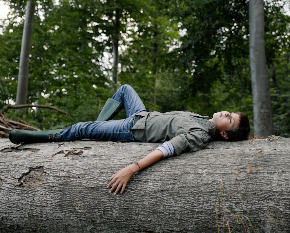 a woman laying on top of a fallen tree