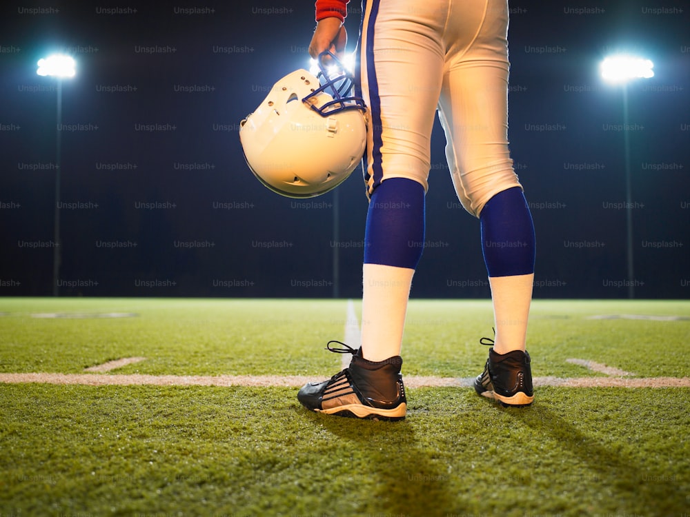 a football player holding a helmet on a field