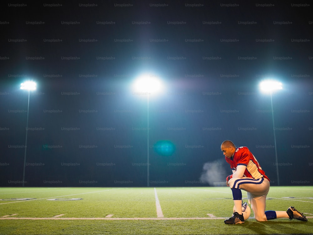a man kneeling down on a football field