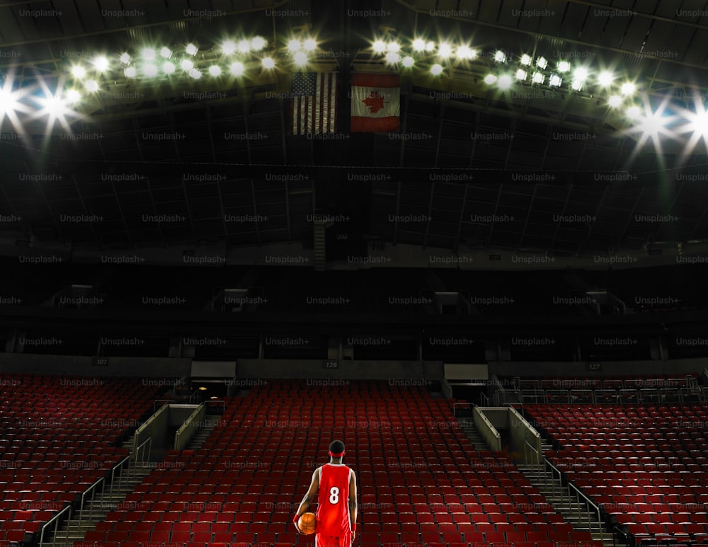 a basketball player in a red uniform standing in a stadium