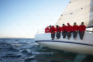 Eine Gruppe von Männern, die auf der Vorderseite eines Segelbootes sitzen