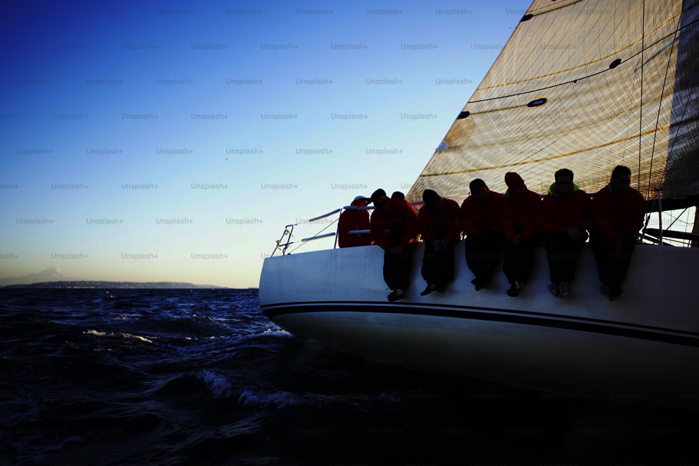 a group of men sitting on the front of a sailboat