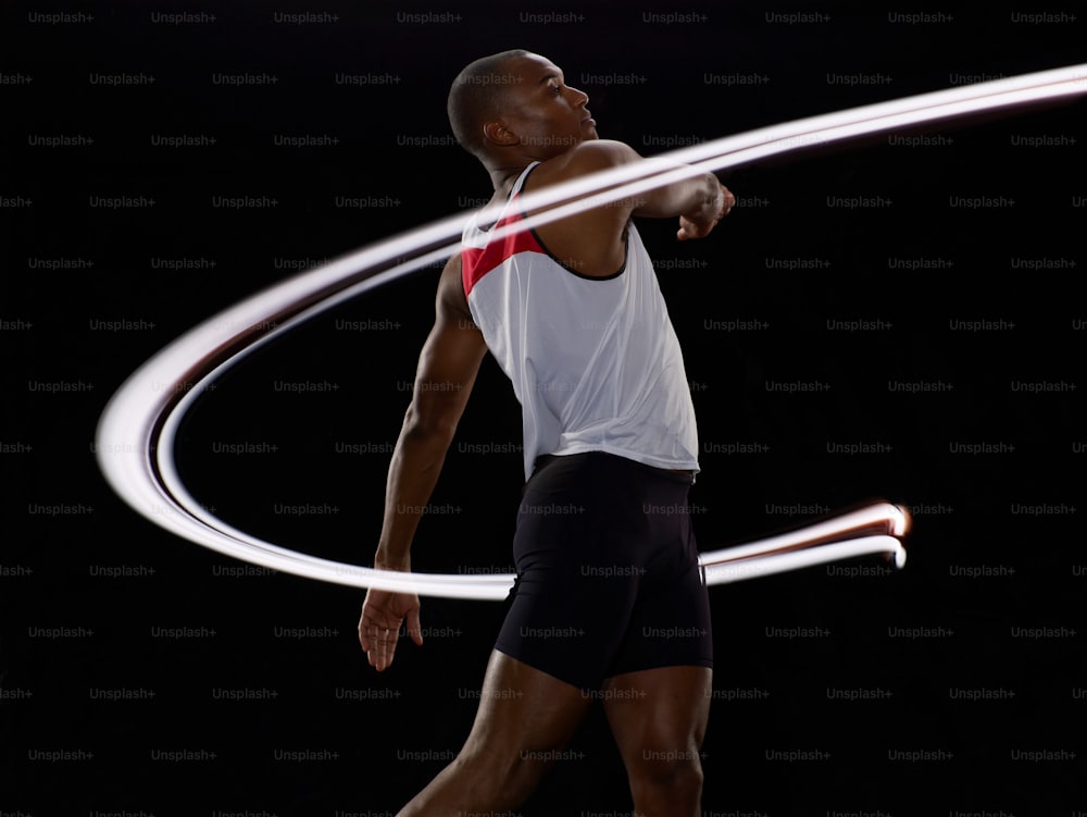 a man in a white tank top and black shorts playing with a hula hoop