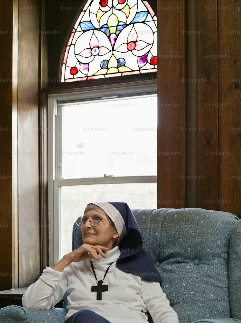 a woman sitting in a chair in front of a stained glass window