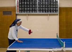 a woman is playing ping pong in a gym