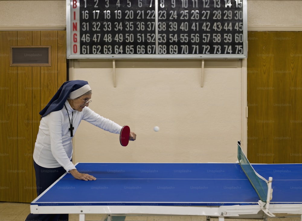 Uma mulher está jogando pingue-pongue em uma academia