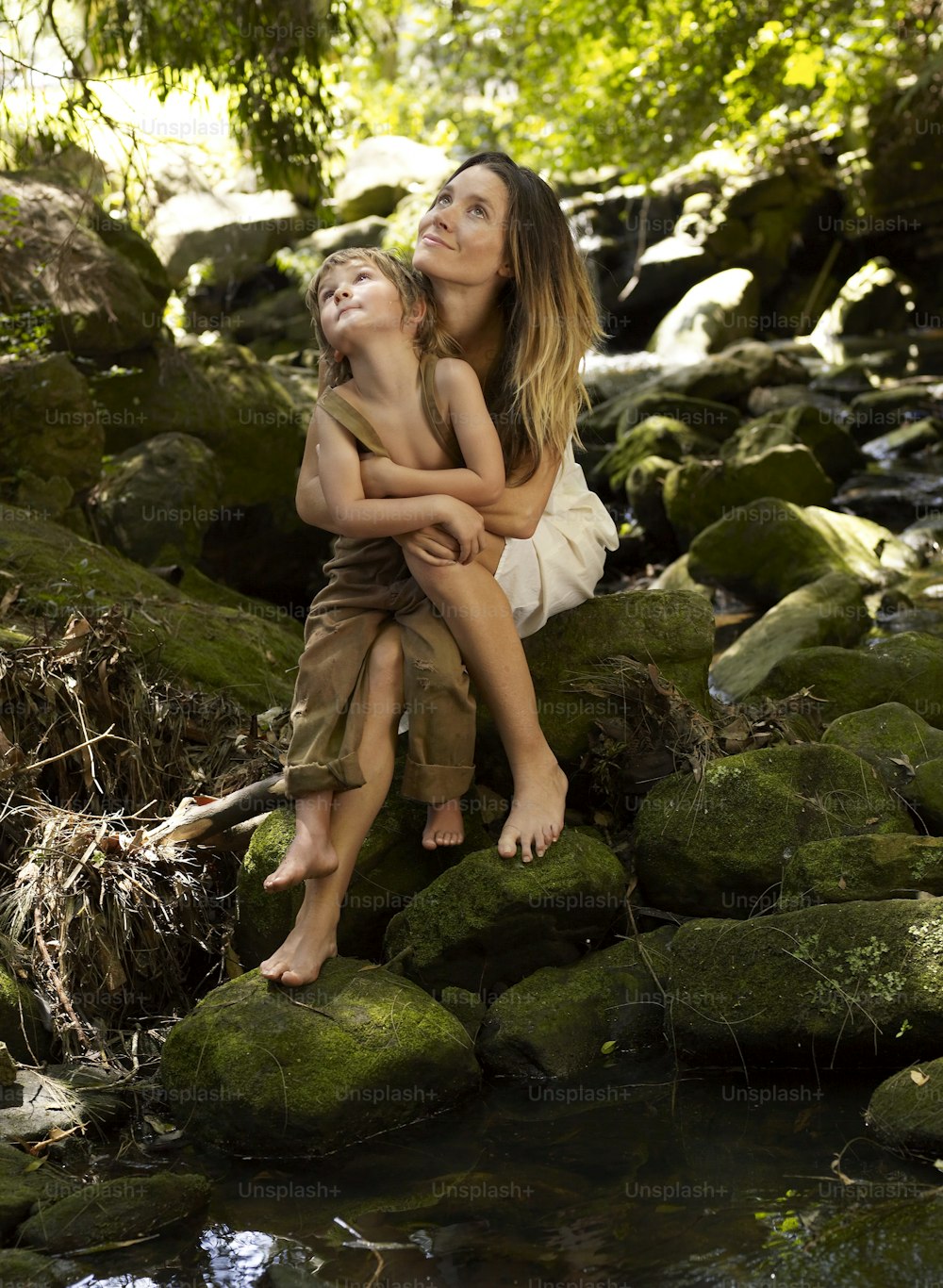 a woman and a child are sitting on some rocks