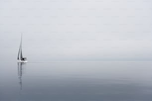 a sailboat in the middle of the ocean on a foggy day