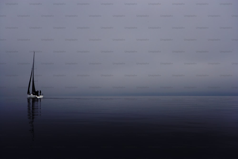 a sailboat in the middle of the ocean on a foggy day