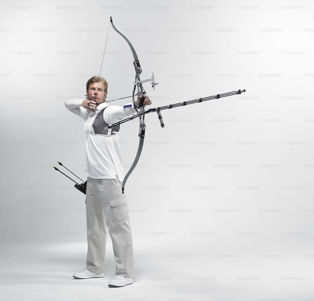 a man in white shirt holding a bow and arrow