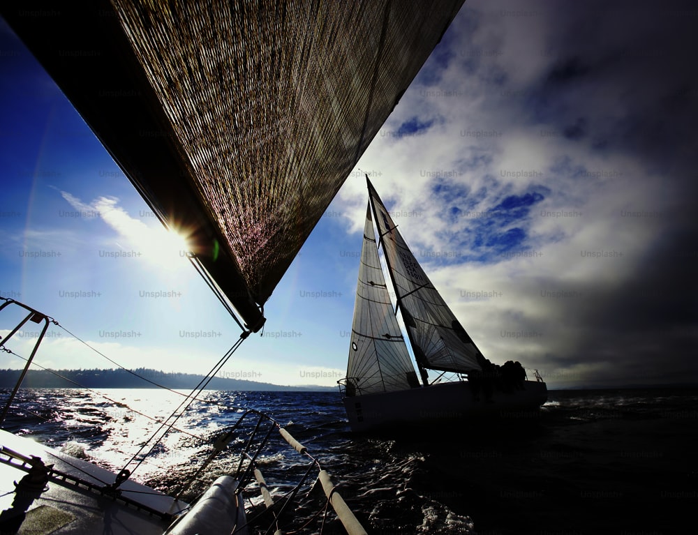 a sailboat sailing on the water with another sailboat in the background