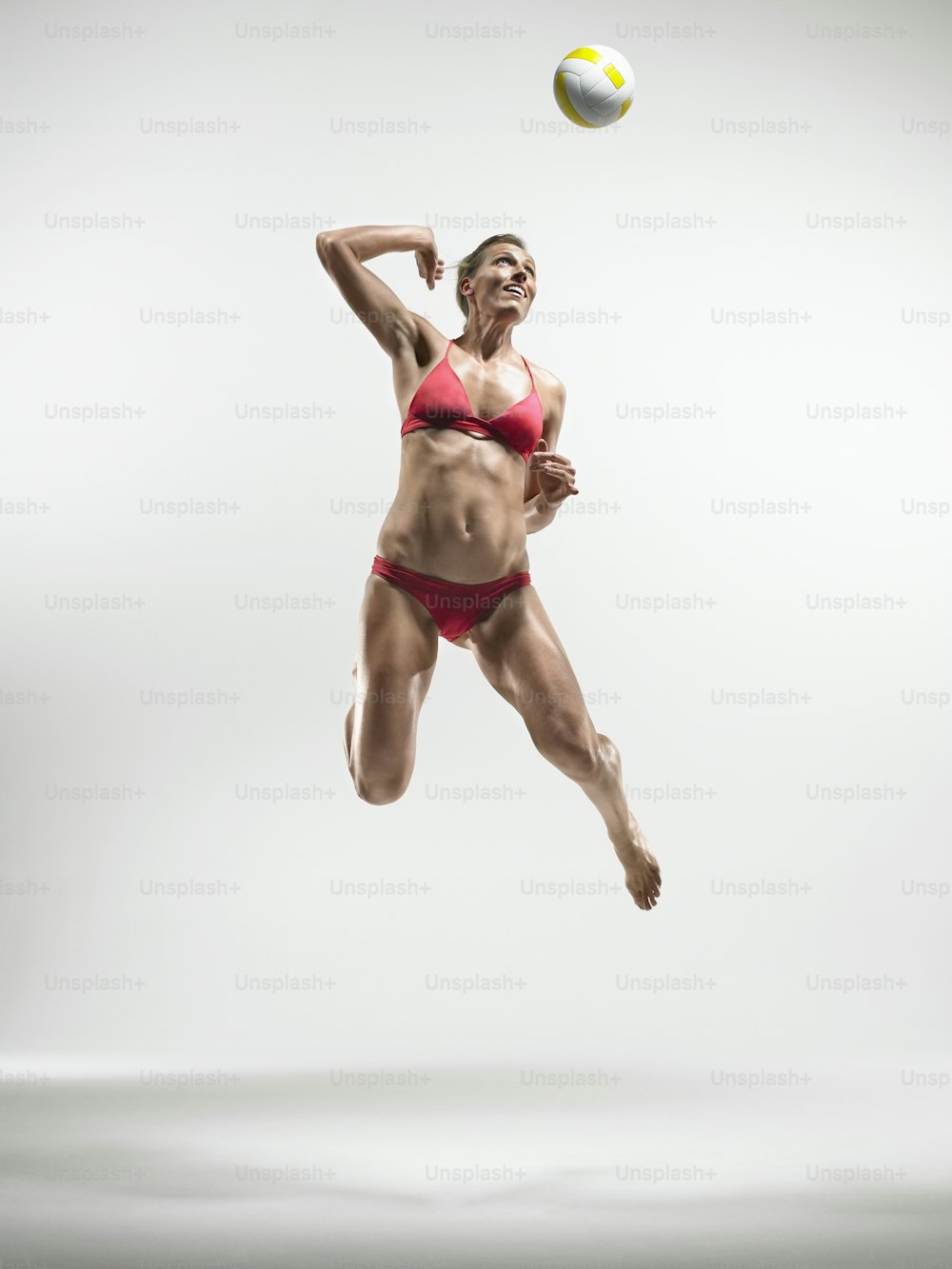 a woman in a bikini jumping in the air to catch a ball
